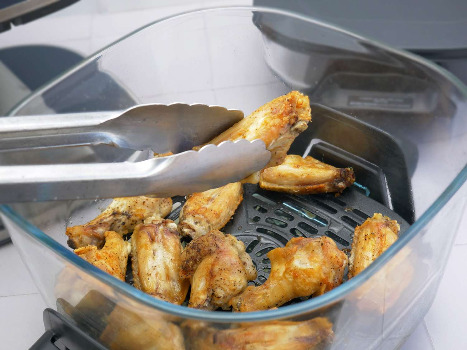 removing a cooked wing from the air fryer with tongs