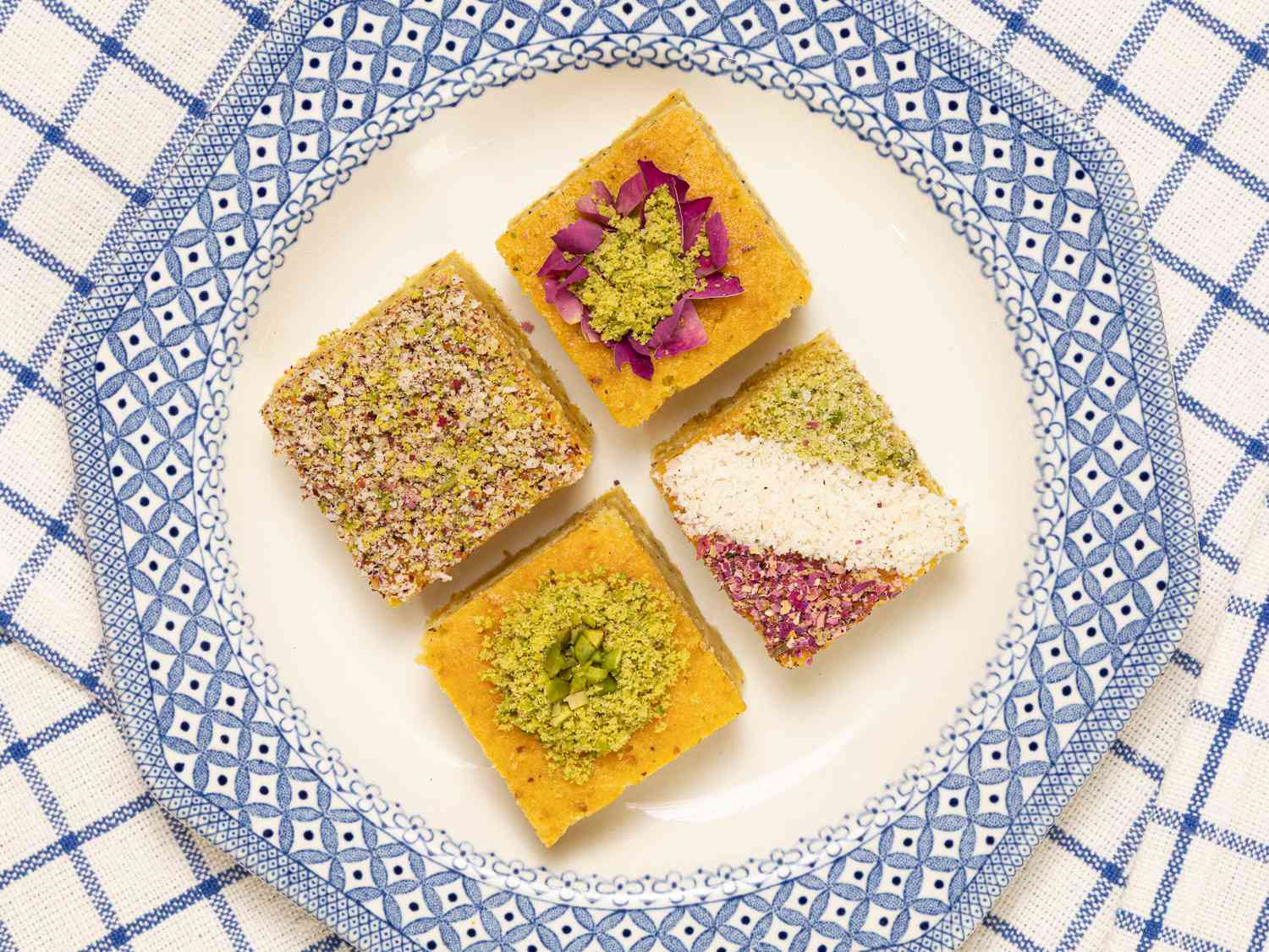 4 baklava cake squares on a white and blue plate, on white and blue checkered fabric