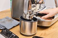 A person removes espresso grounds from the Breville The Oracle Jet Espresso Machine