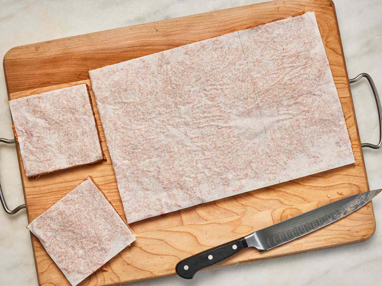 Overhead view of cutting meat sheet into squares.