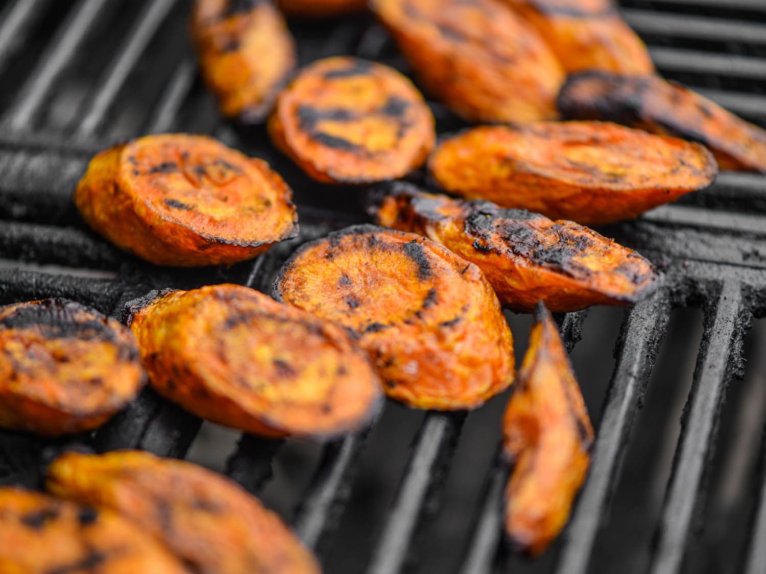 Sliced charred carrots on a grill. 
