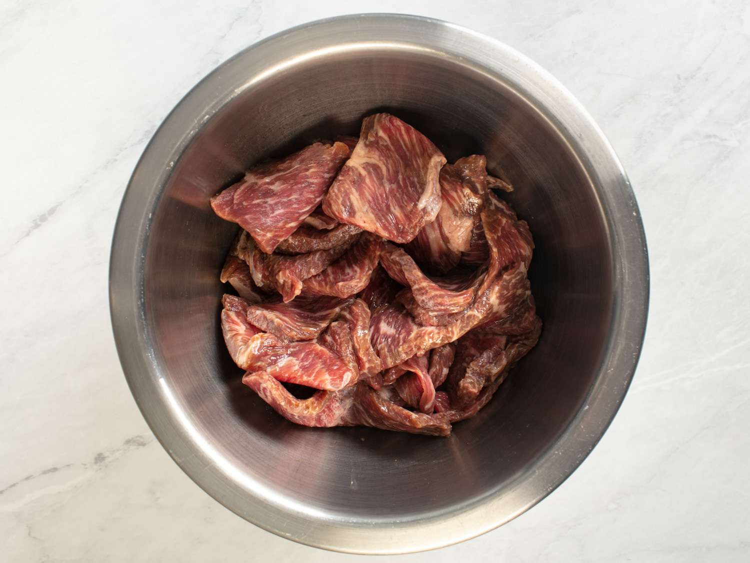Seasoned sliced beef marinating in a mixing bow.