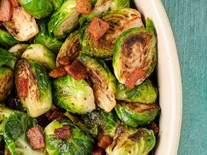 Roasted Brussels sprouts and bacon inside of a ceramic dish.