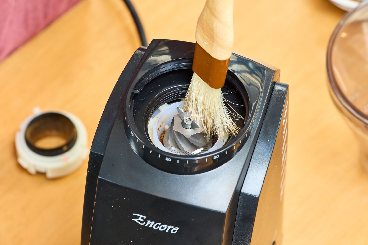 A person brushes the blades on the Baratza Encore Conical Burr Coffee Grinder