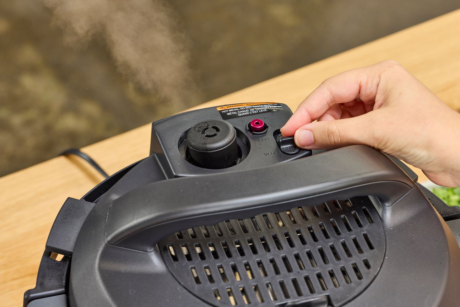 A person adjusts the knob of the Instant Pot Pro 10-in-1 6-Quart Pressure Cooker