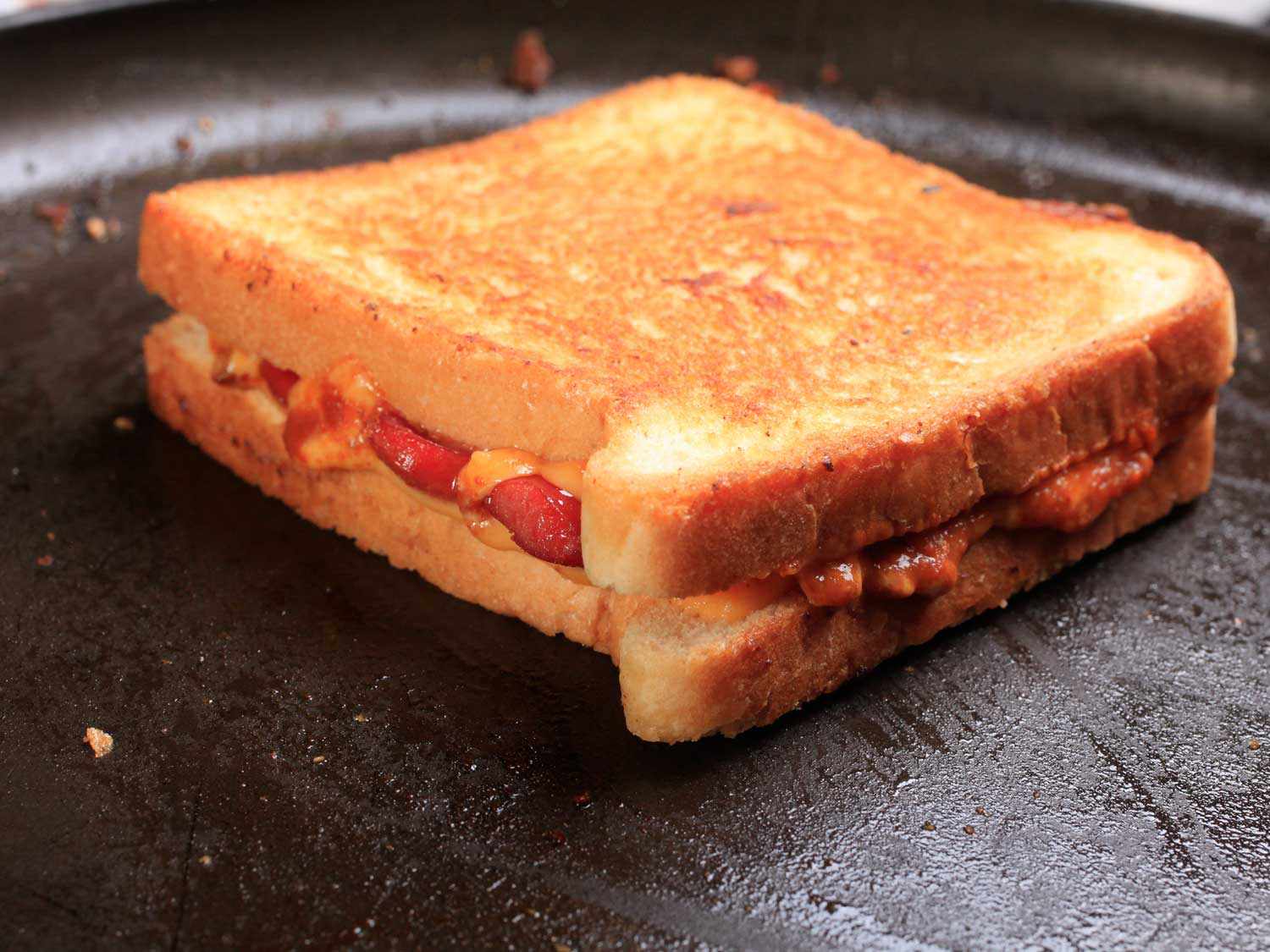 A chili grilled cheese dog finishes cooking in a cast iron skillet.