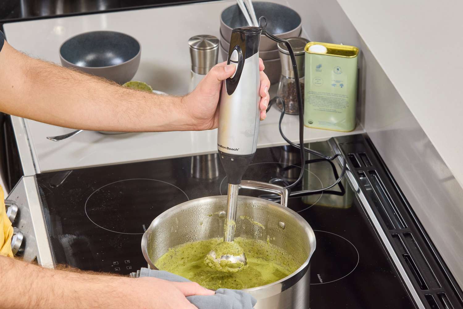 A person uses the Hamilton Beach 2-Speed Hand Blender to make soup