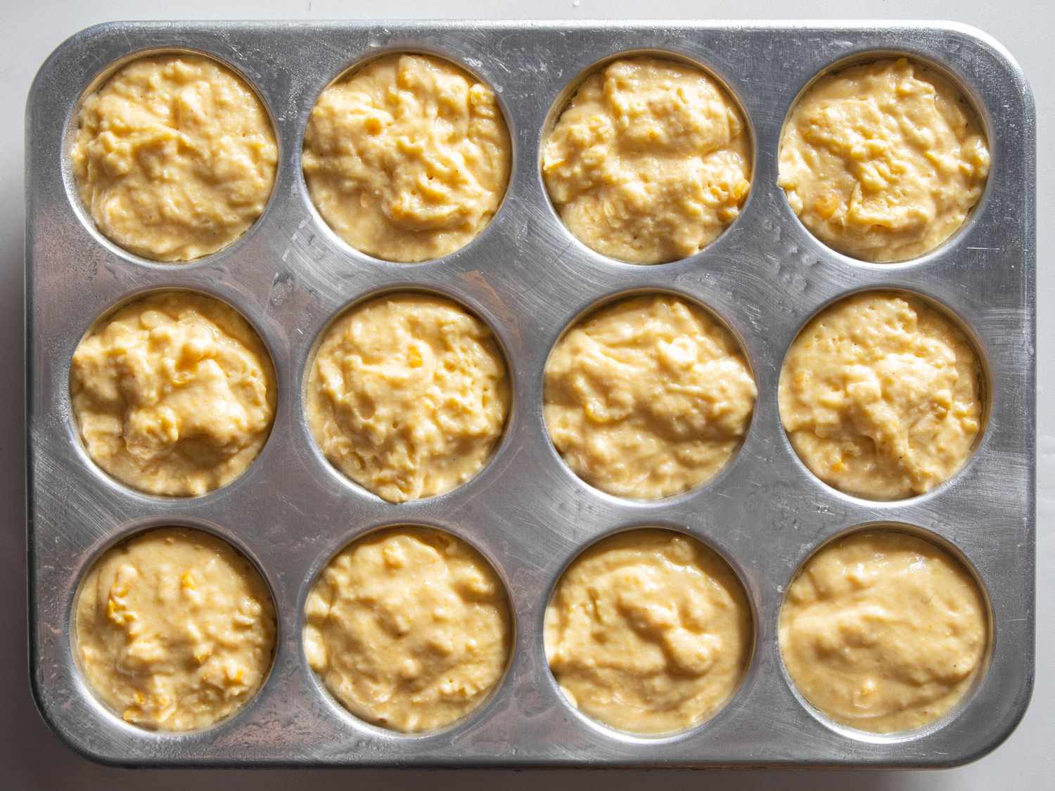 Muffin tin filled with cornbread muffin batter