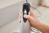 A person presses a button on the Hamilton Beach 2-Speed Hand Blender