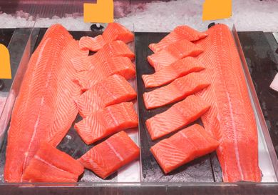 Slices and fillets of salmon arranged on display in a storefront or market counter