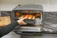 a person putting a pan pizza into a pizza oven