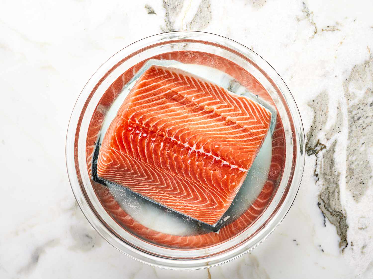 Overhead view of salmon in a bowl of salty water