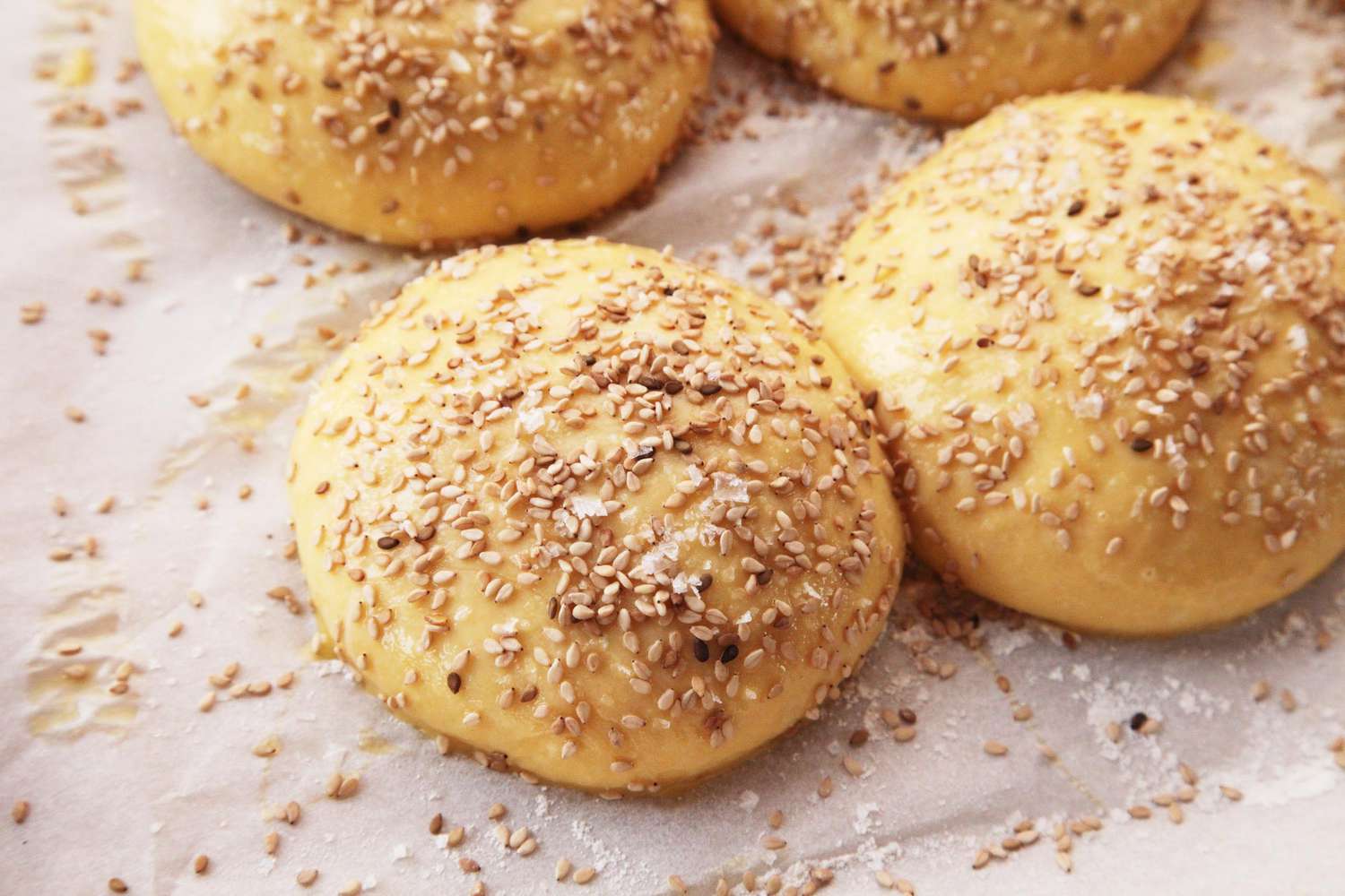 The brushed, unbaked buns are sprinkled liberally with sesame seeds.