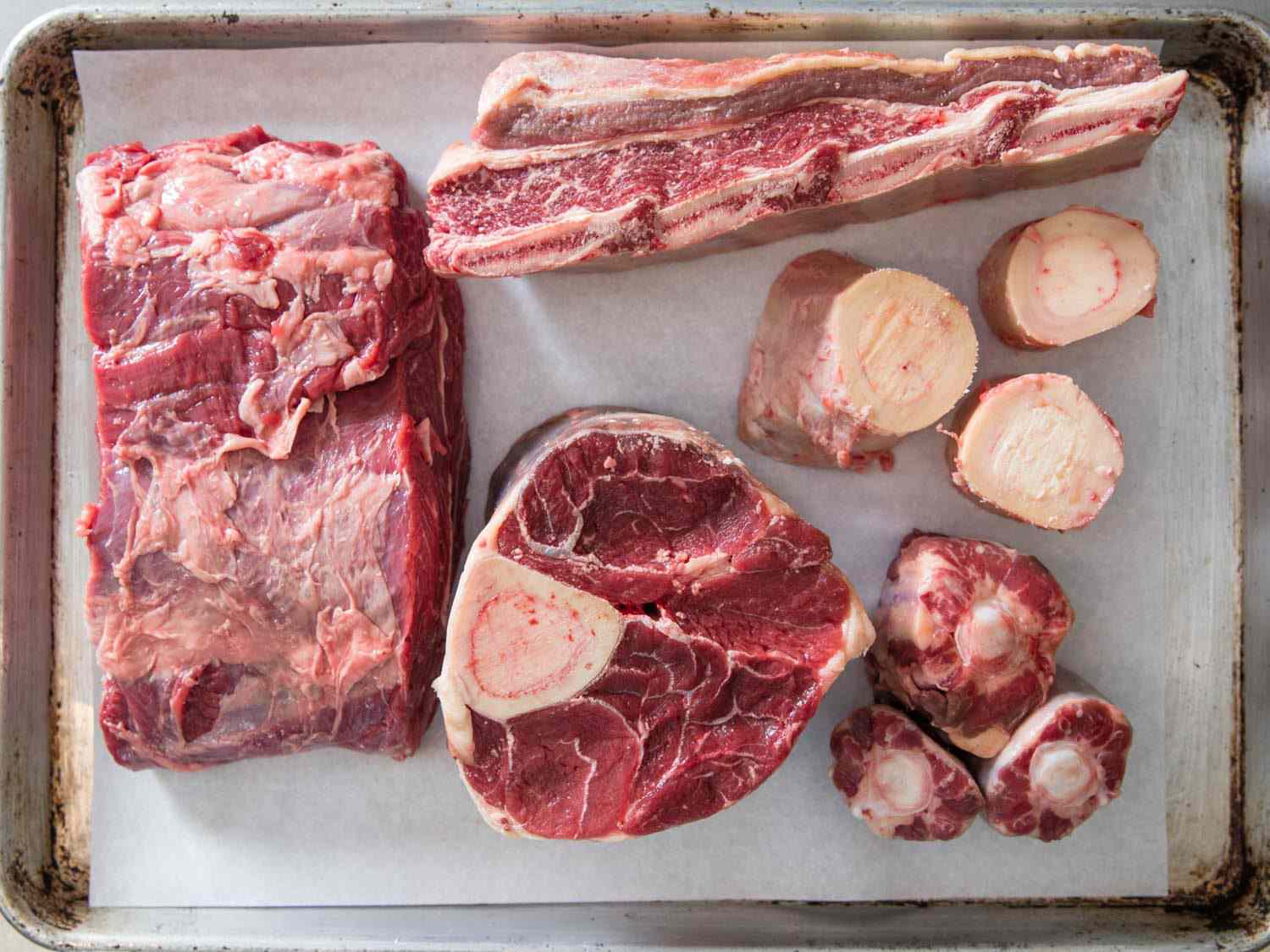 Different cuts of beef on a sheet tray.