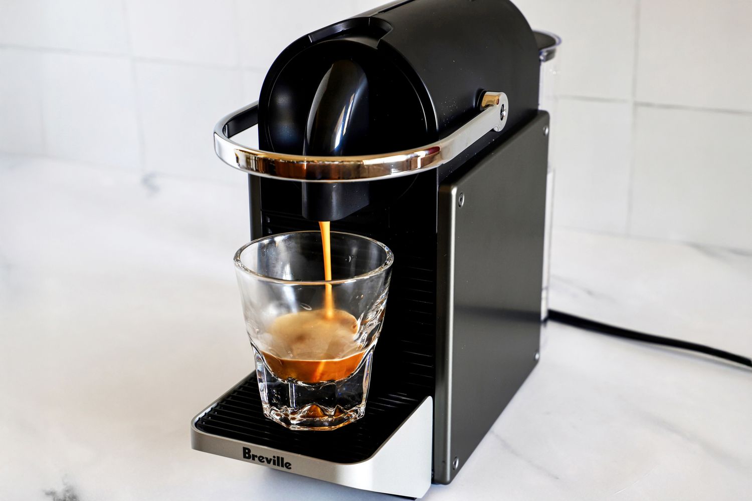 A coffee machine brewing espresso into a clear glass cup