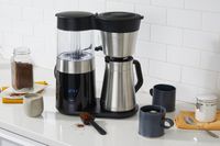The OXO Brew 9-Cup Coffee Maker with thermal carafe on a kitchen counter surrounded by coffee mugs