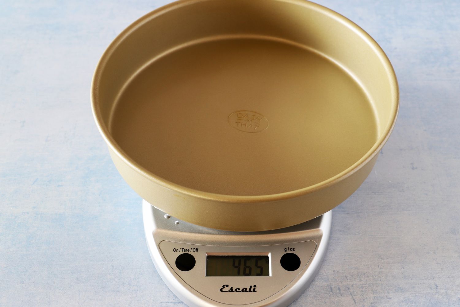 A kitchen scale with an empty cake pan on it.