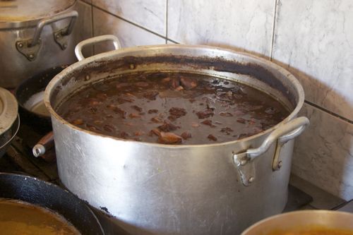 A large pot of feijoada simmers on a back burner.