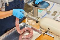 Close-up of person making sausage using KitchenAid KSMMGA Metal Food Grinder Attachment