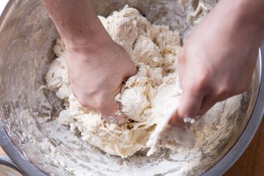 Someone mixing and kneading bread dough by hand. 