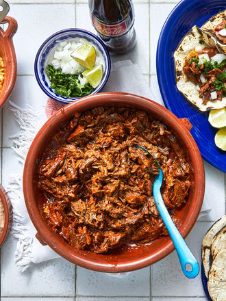 Overhead view of bowl of birria and assorted sides
