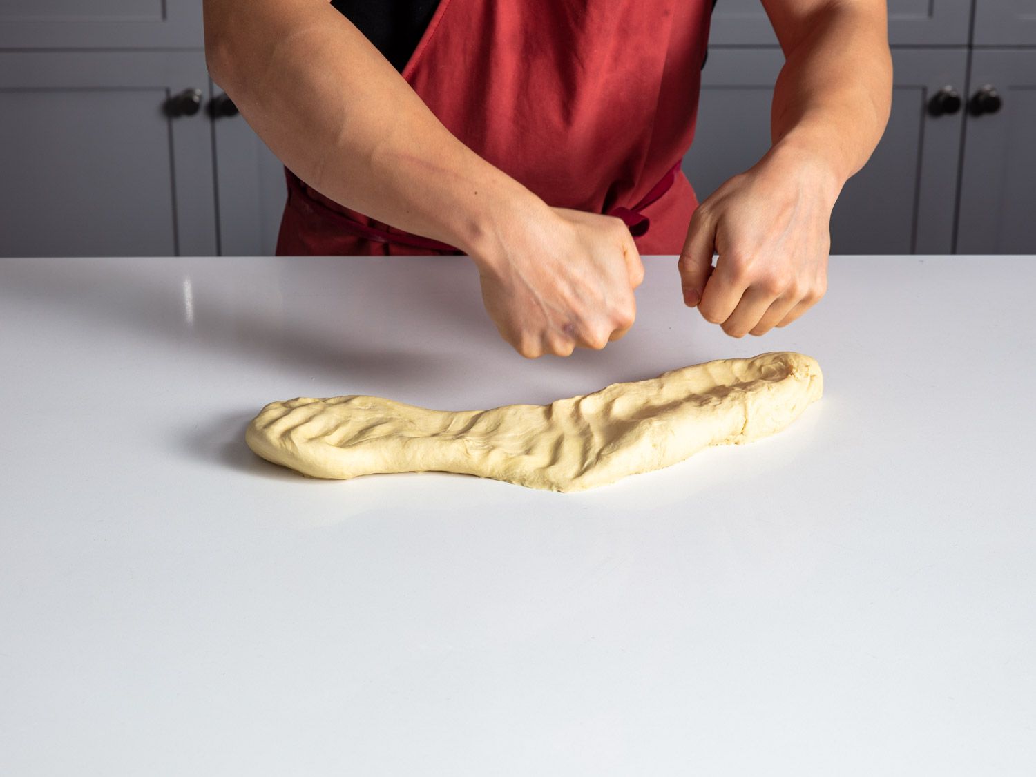 Homemade lamian noodle dough being punched with fists.