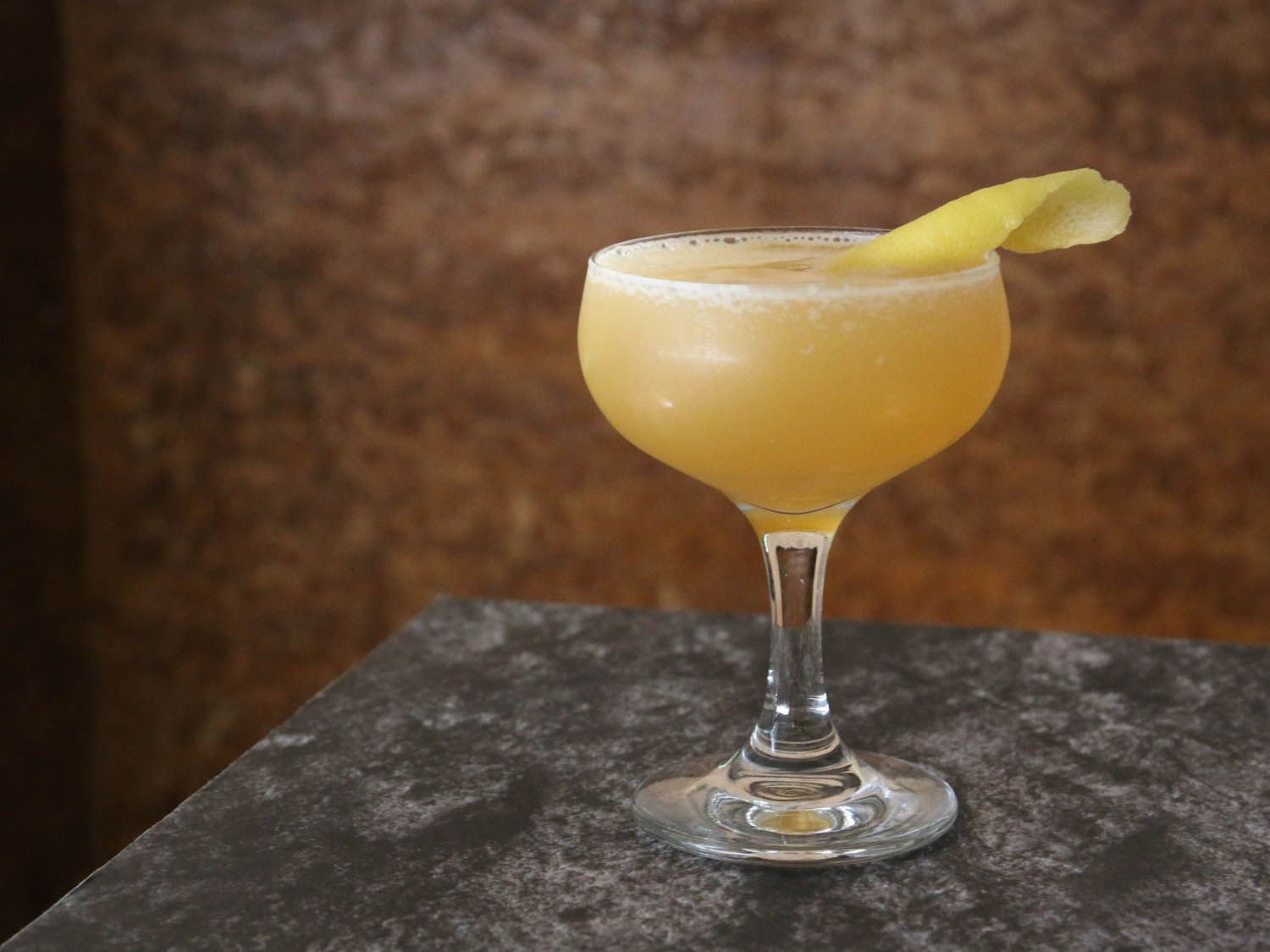 A sidecar cocktail served in a coupe glass with a lemon twist.