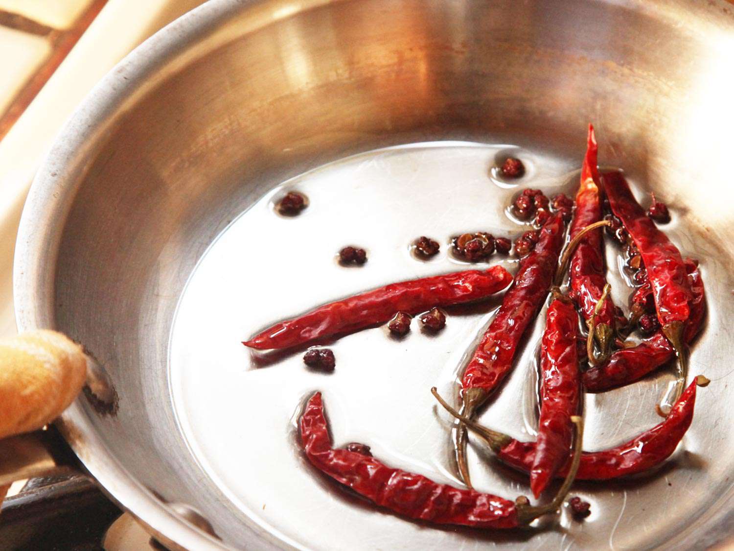Dried whole chiles and Sichuan peppercorns are gently fried in a small skillet.