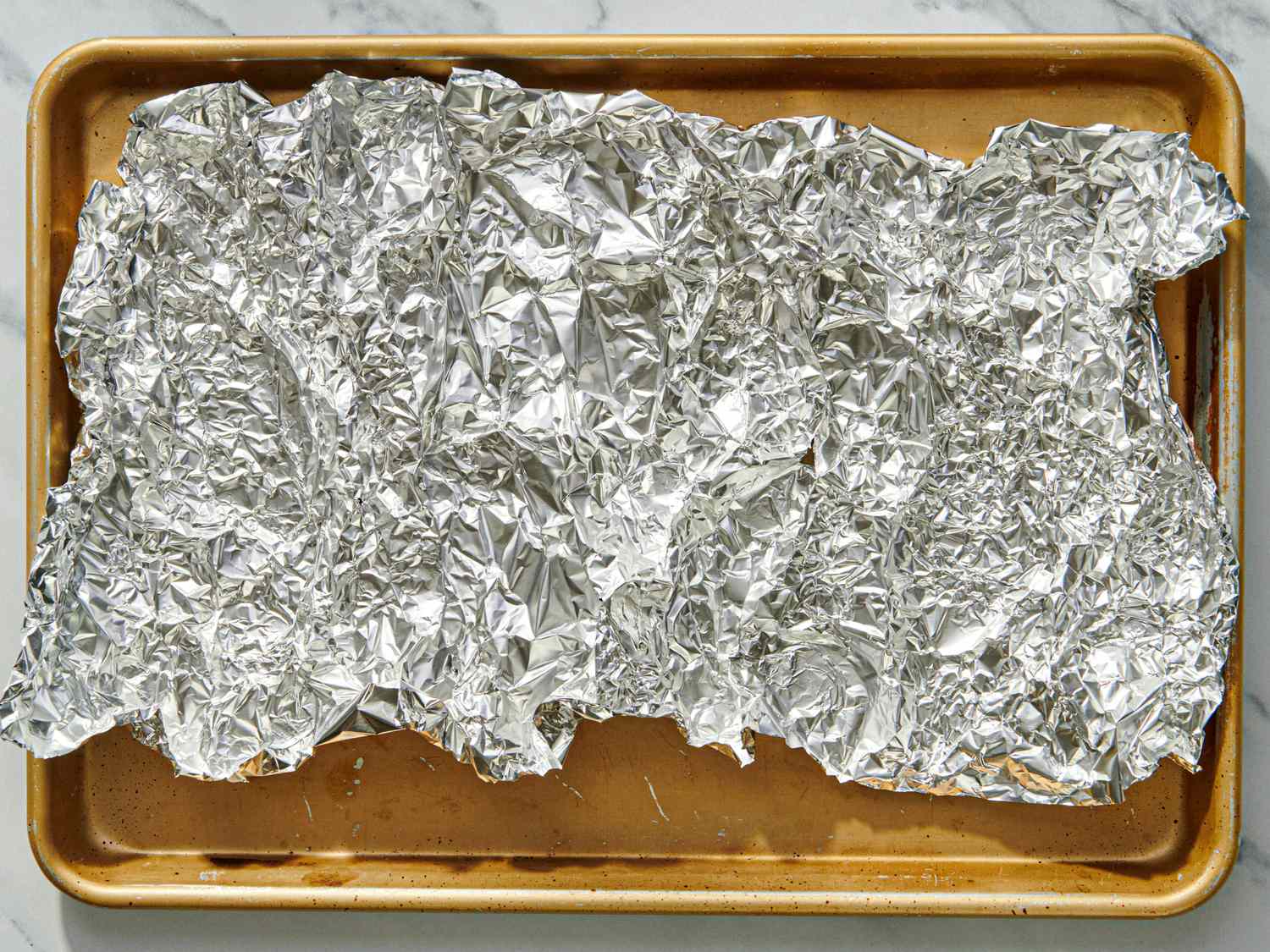 A baking tray covered with crumpled aluminum foil