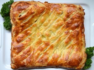 A square baked chicken and leek pie in puff pastry on a platter