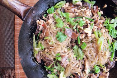Overhead view of Glass Noodles with Chicken and Mushrooms, served straight from a wok.
