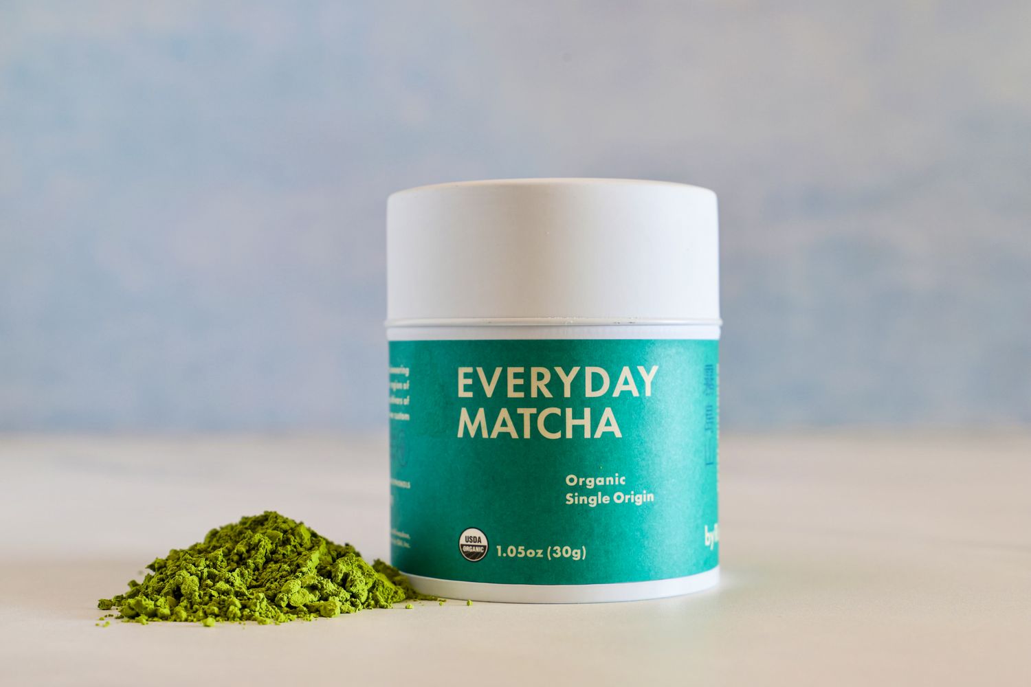 A container of Rishi Tea Everyday Matcha next to a pile of the powder