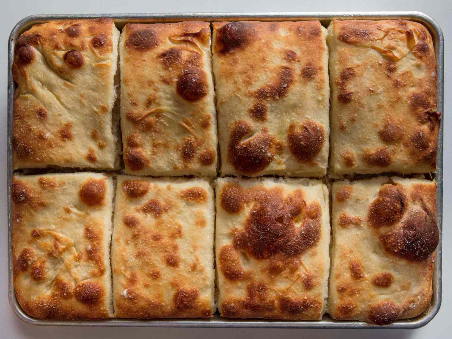 Overhead shot of tray of baked squares of pizza.