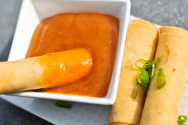 Fried egg roll being dipped in homemade duck sauce