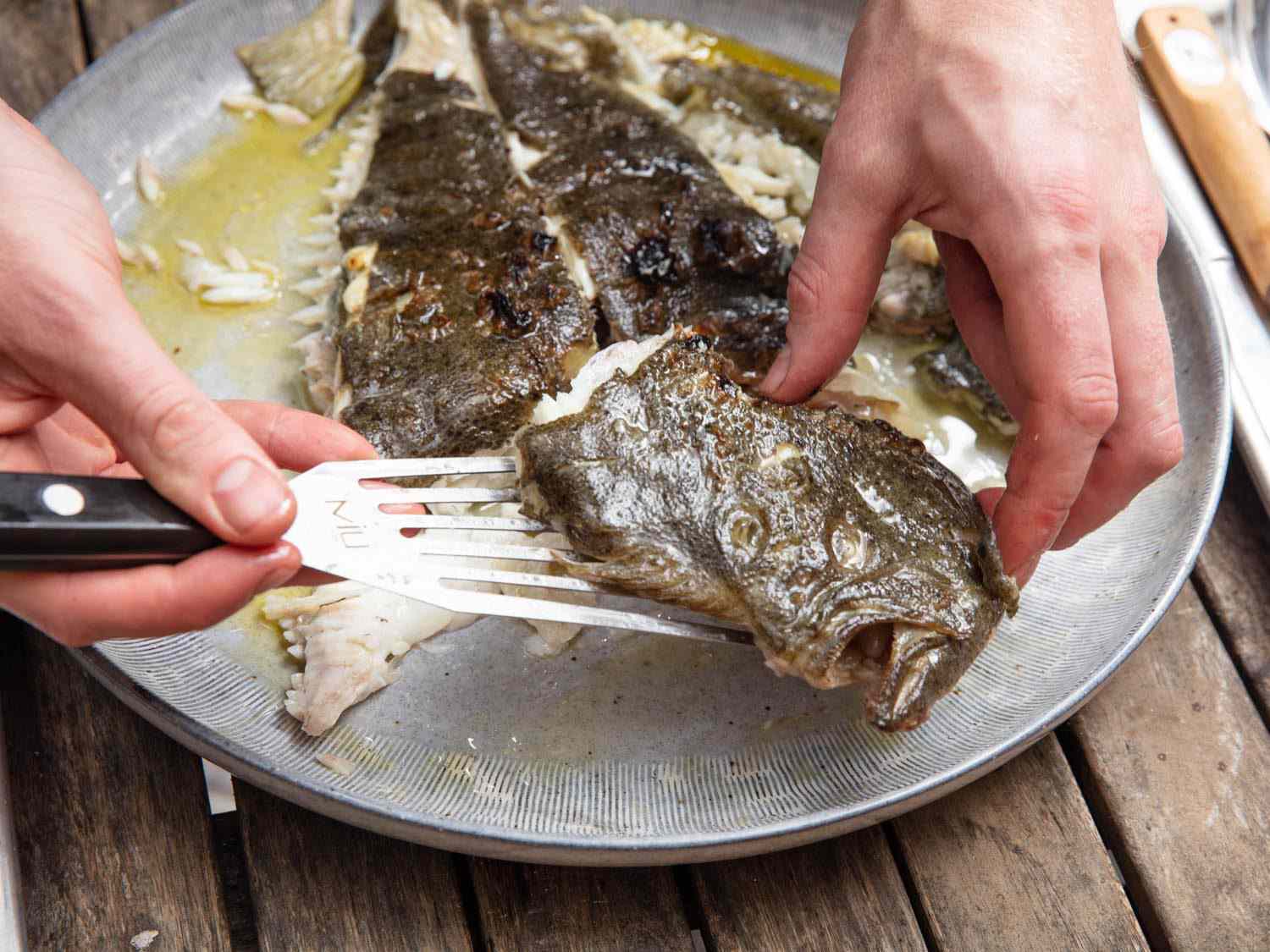 Separating the turbot head from the rest of the fish after grilling.
