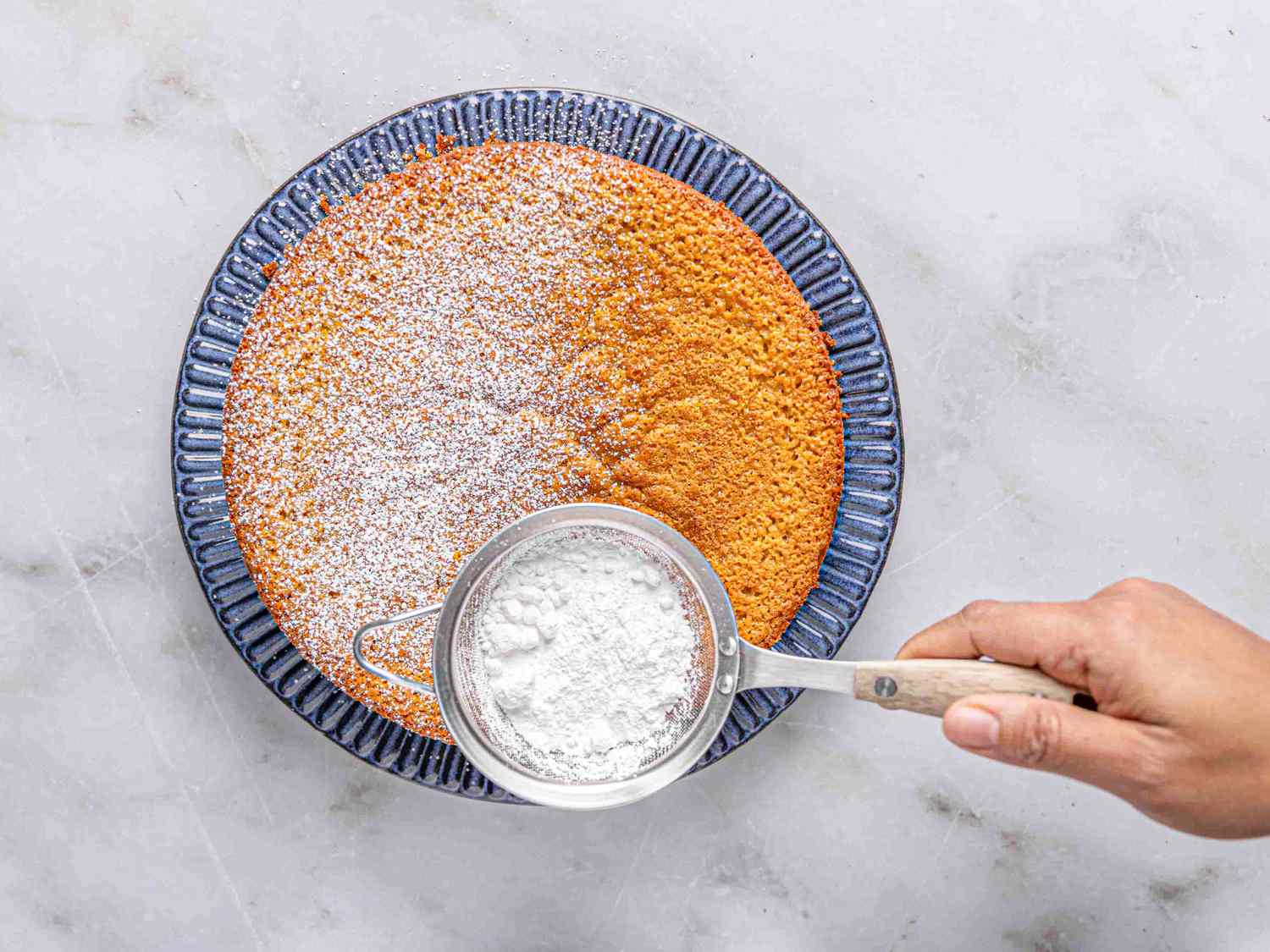 Overhead view of dusting cake with sugar