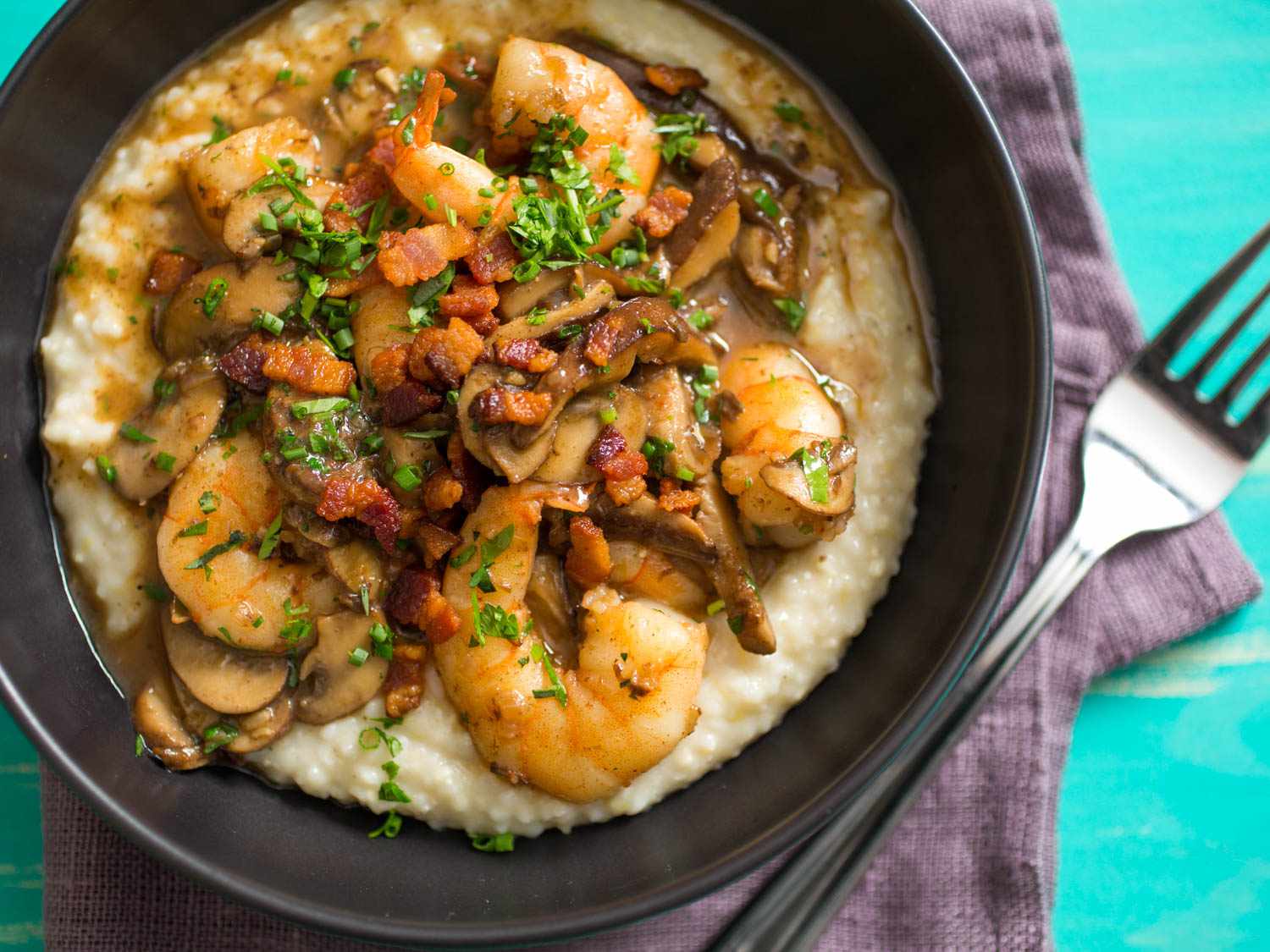 Overhead shot of cheesy grits topped with sauteed shrimp, mushrooms, and bacon.