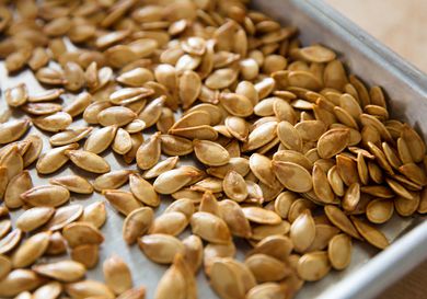 Closeup of roasted pumpkin seeds on a rimmed baking sheet.