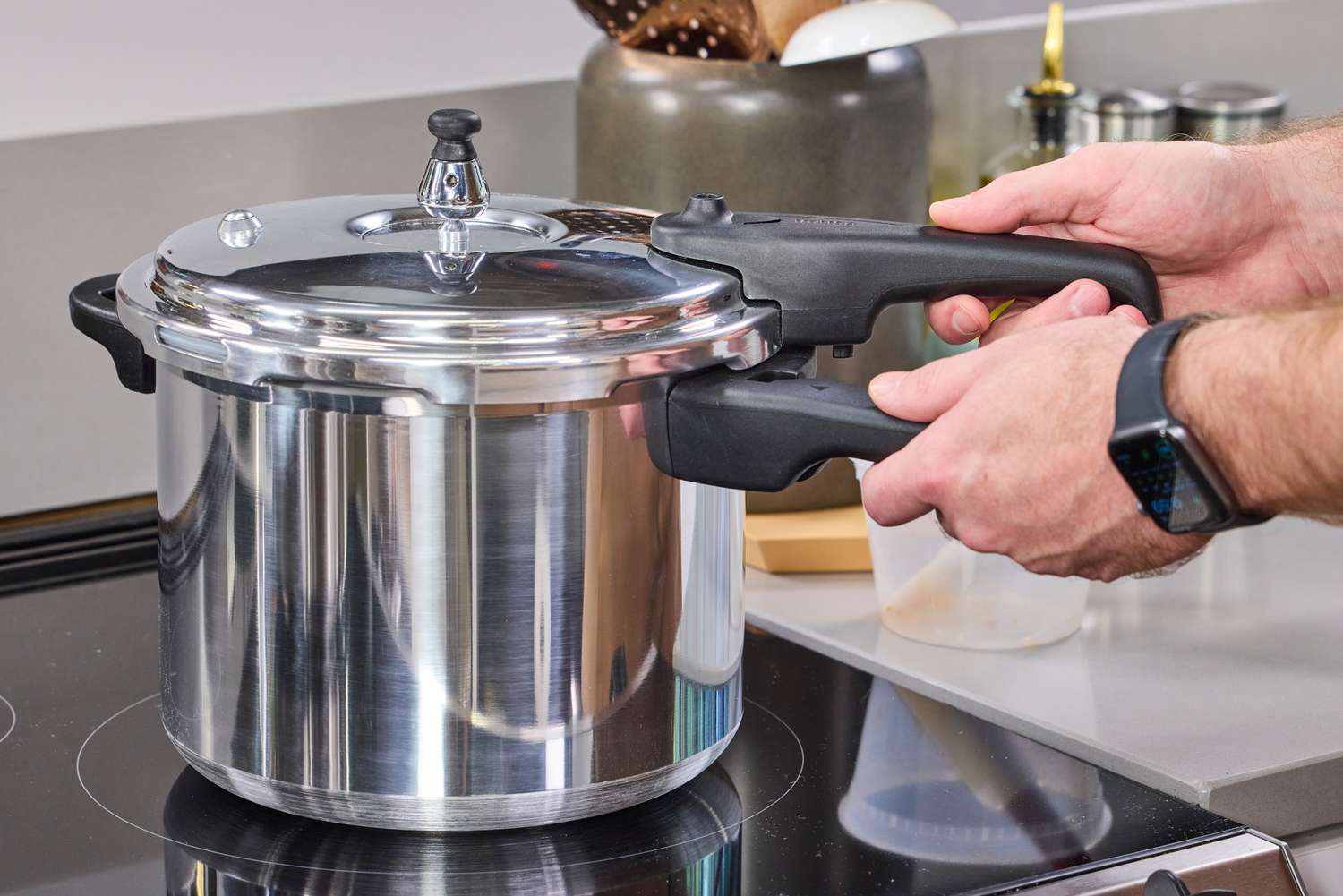 A person removes the lid on the IMUSA 7 Quart Stovetop Aluminum Pressure Cooker