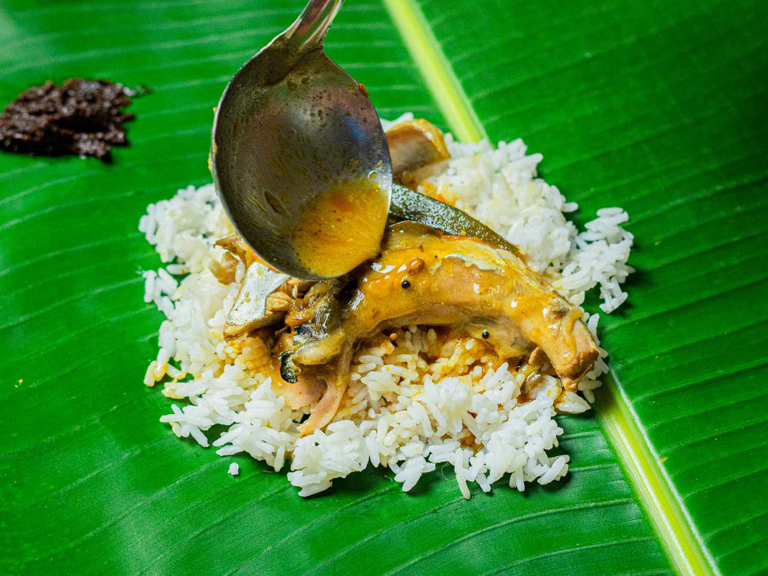 Overhead view of spooning curry onto fish