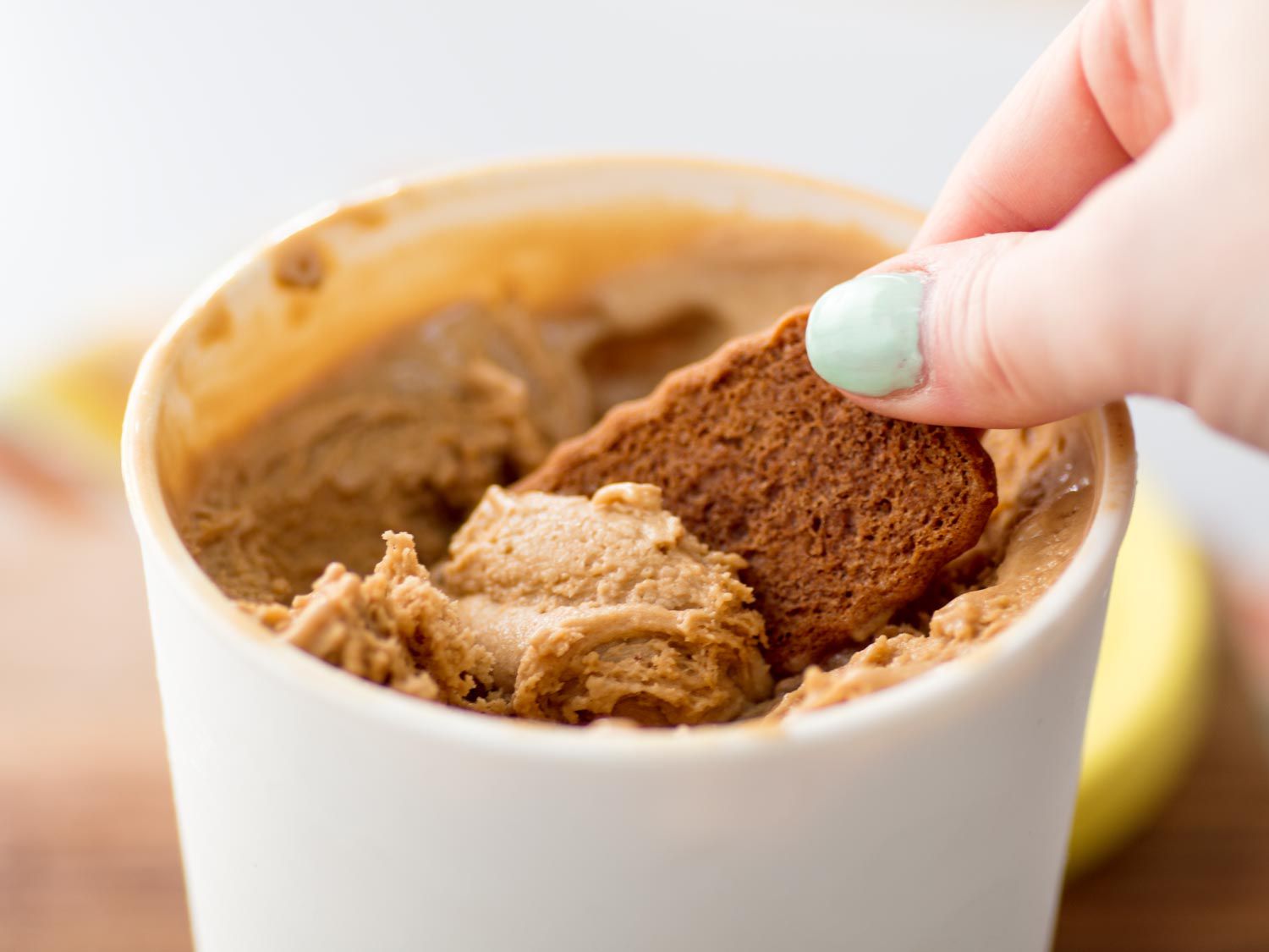 The author scoops speculoos ice cream out of the container with a speculoos cookie.
