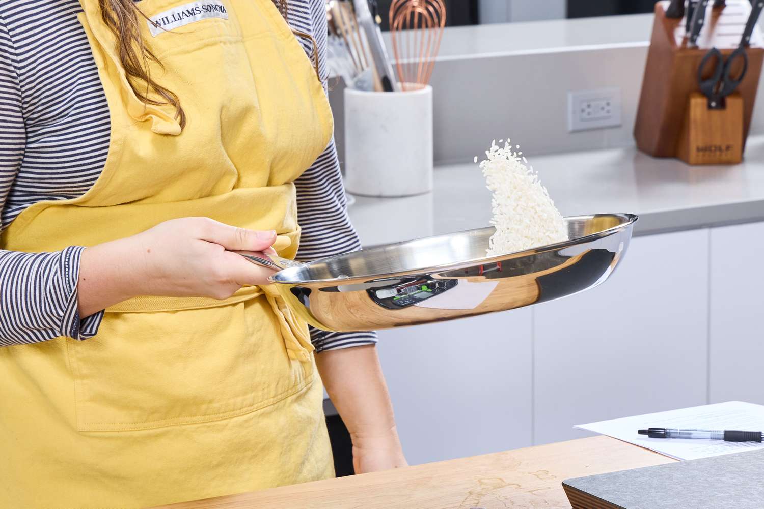 A person flips rice in the Le Creuset 12 Inch Large Tri-Ply Stainless Steel Fry Pan