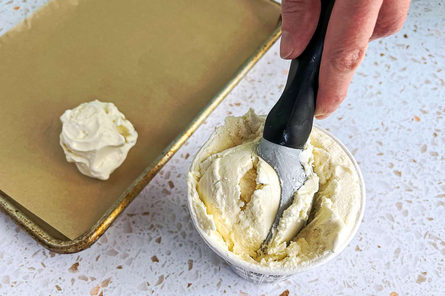 a person using the gorilla grip ice cream scoop to serve vanilla ice cream