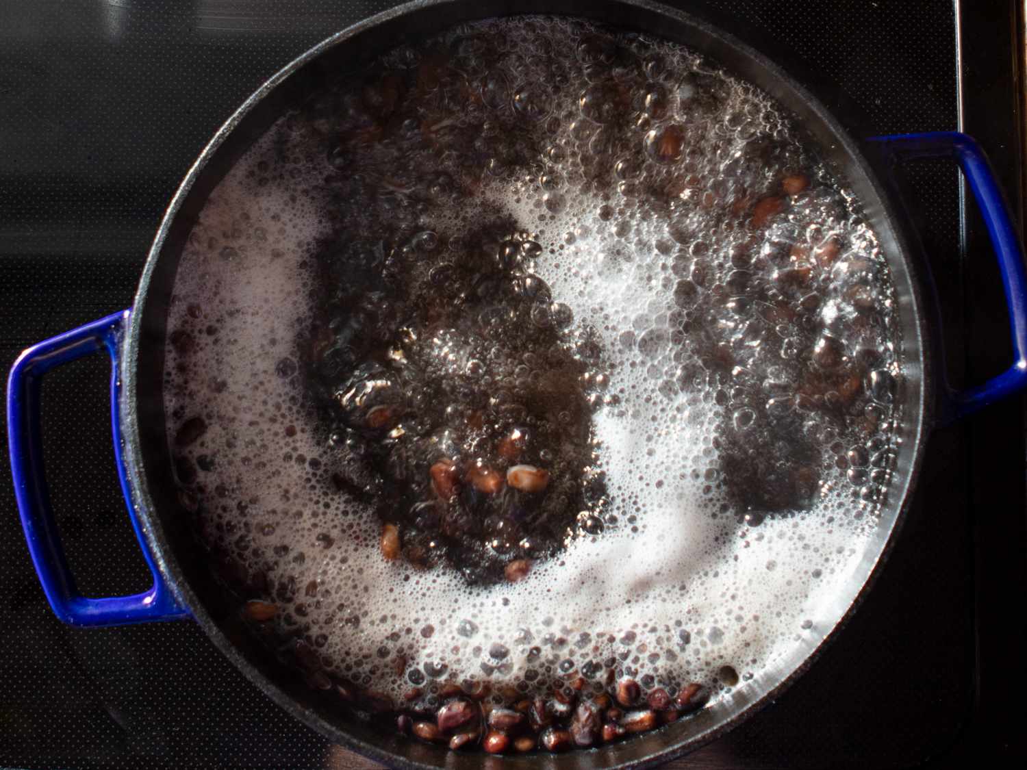 njahi beans in boiling water on a stovetop in a dutch oven