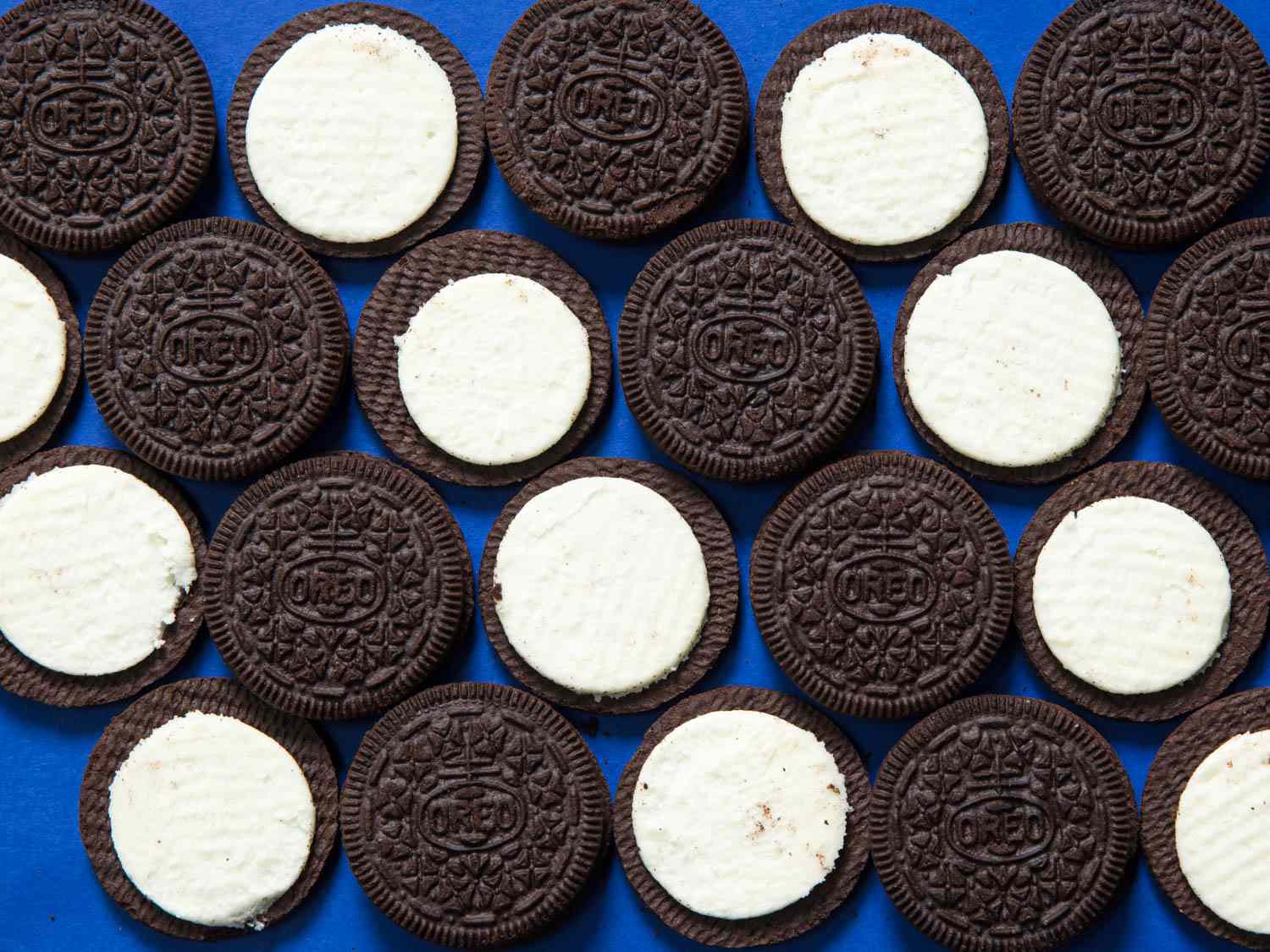 Diagonal rows of Oreos split open to show both the tops of the cookies and the frosting-filled layers.