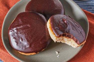 3 cookies on a grey plate, one cookie has bite marks taken out of it. Plate is on red napkin on a blue tablecloth 