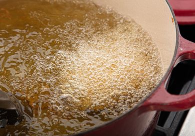 A pot of oil is bubbling while food is being fried