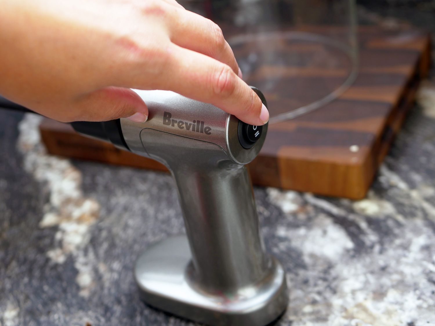 hand pressing on button on breville smoking gun