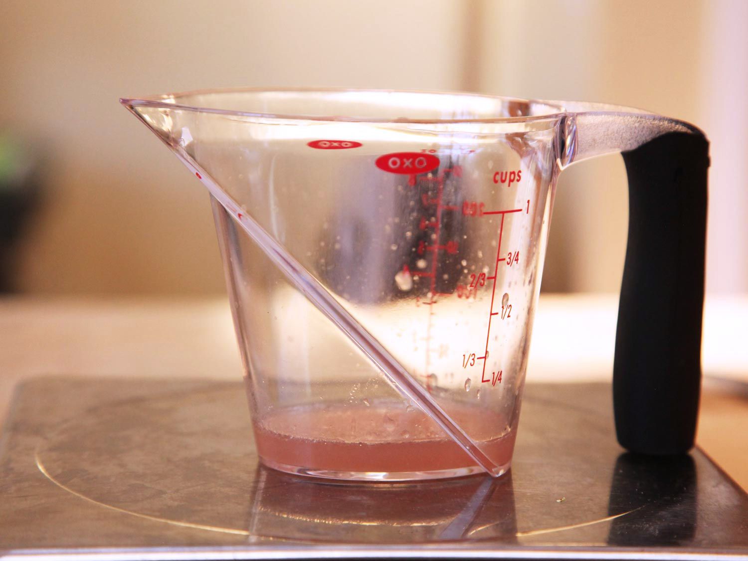 Liquid measuring cup of liquid expressed from chicken breast cooked sous vide to 140 degrees Fahrenheit.