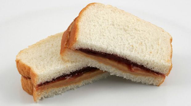 Peanut butter and jelly sandwich on white sliced bread, cut in half with the cut sides facing the camera. 